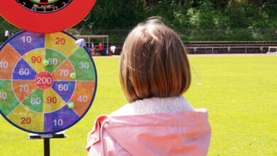 a girl in a pink jacket sitting in front of a dart board