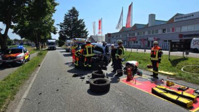 a group of firefighters standing around a car that has been crashed