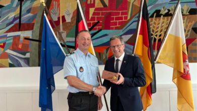 two men shaking hands in front of flags
