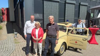 a group of people standing in front of a yellow car