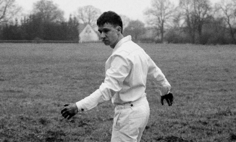 a man in a white shirt and black gloves walking in a field