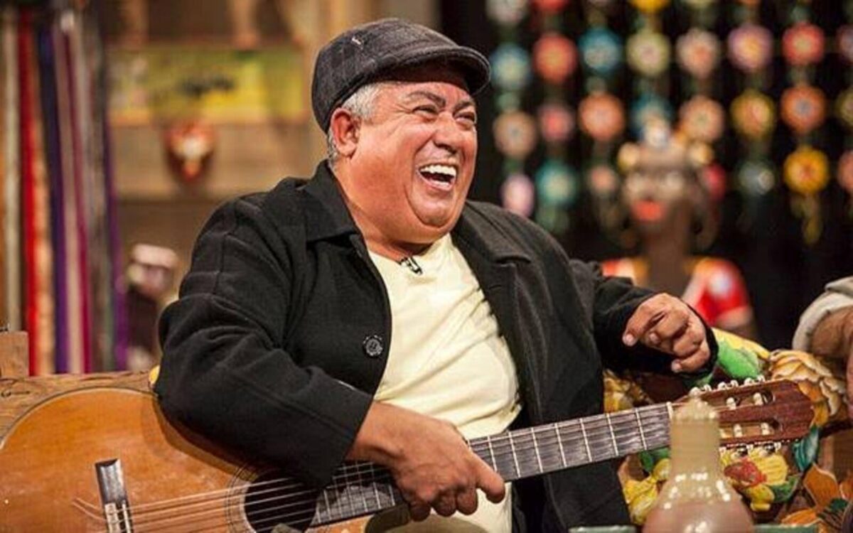 a man laughing while holding a guitar