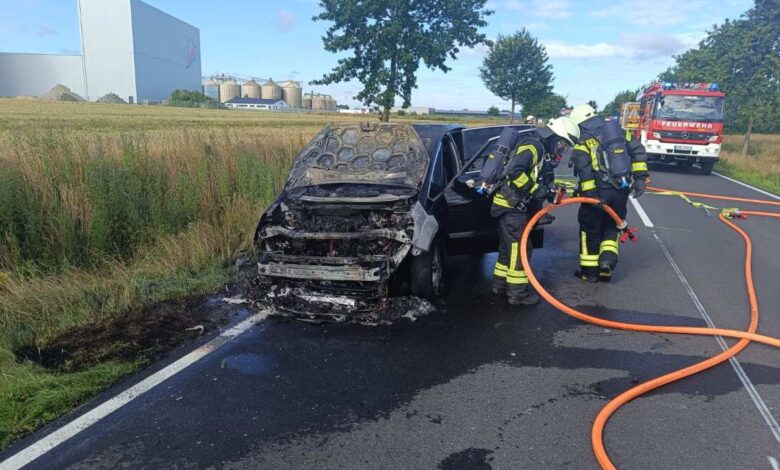 Ford fängt während der Fahrt Feuer – Familie rettet sich rechtzeitig 5 firefighters putting out a burnt out car on a road