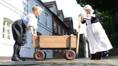 a woman pushing a wooden cart with a woman in a white dress