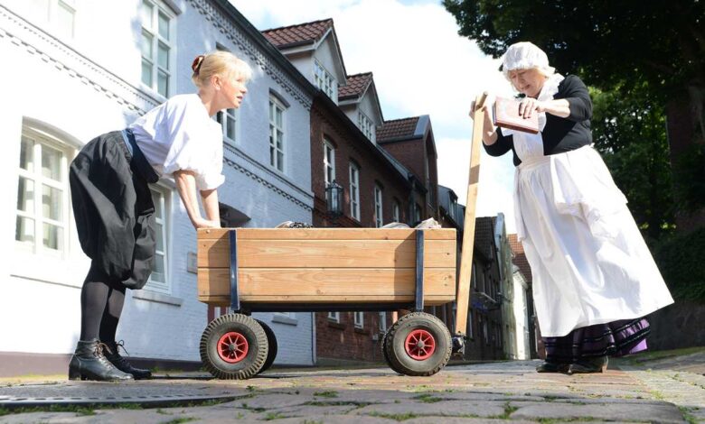 a woman pushing a wooden cart with a woman in a white dress