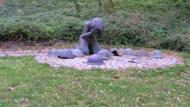 a statue of a man kneeling in a circle of round objects