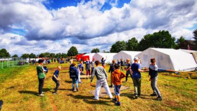 a group of people standing in a field with tents