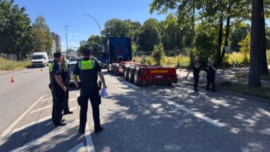 a group of police officers standing in front of a semi truck