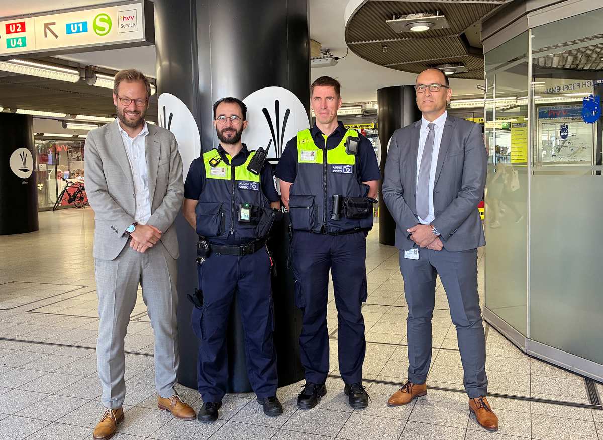 Hochbahn-Wache setzt auf Bodycams: Neuer Schritt für mehr Sicherheit im Nahverkehr 1 a group of men standing in front of a pillar