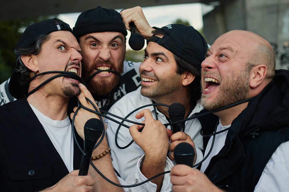 Vier Männer mit Mikrofonen zusammen.