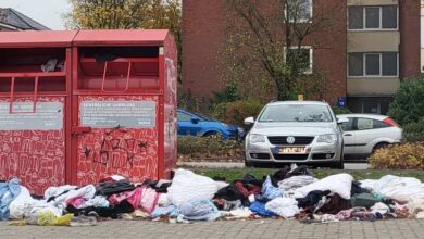 a pile of clothes in front of a trash can