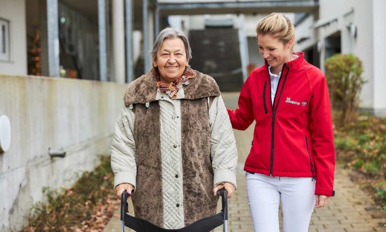 Die Leistungen der Pflegeversicherung – Vortrag der Johanniter in Meckelfeld 10 Pflegekraft unterstützt ältere Dame beim Gehen.