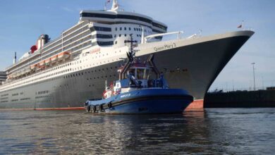 a boat in the water next to a large cruise ship