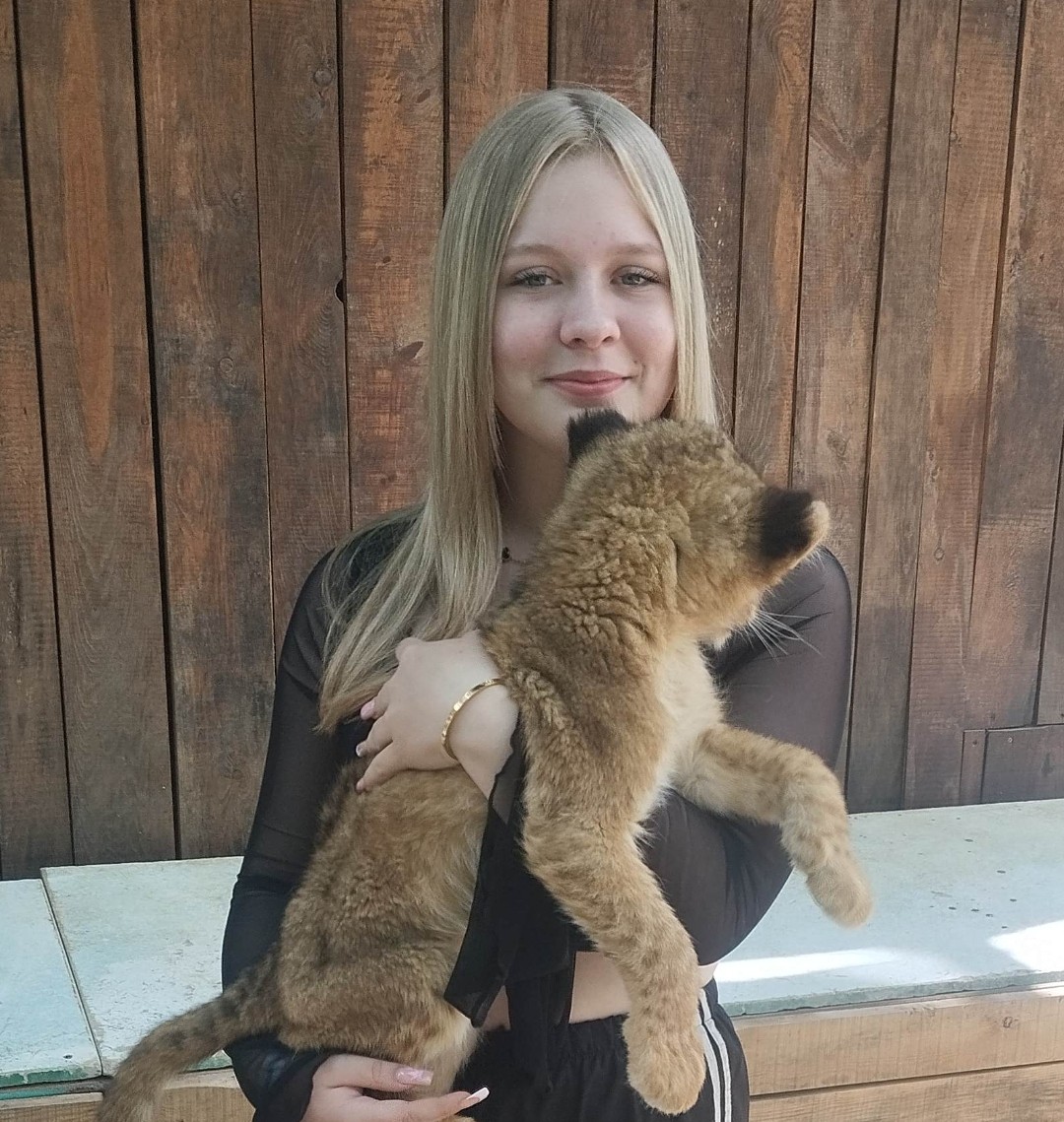 Frau hält Löwenjunges in den Händen.