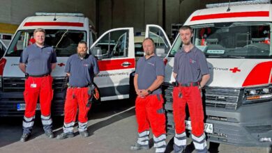 Rettungsdienstmitarbeiter vor Einsatzfahrzeugen.