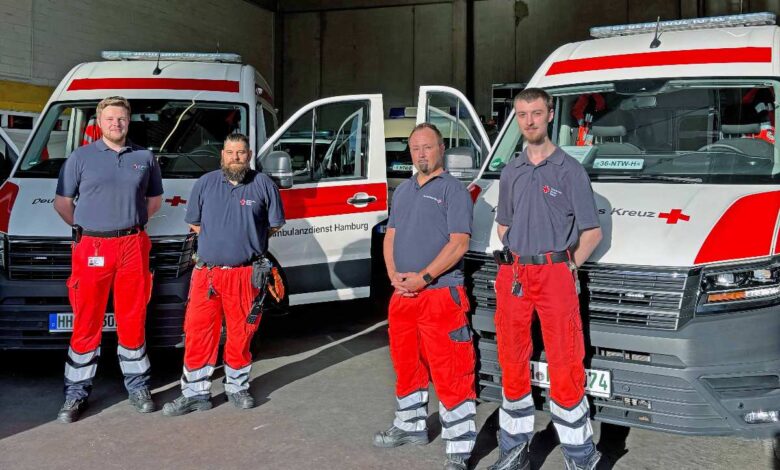Mehr Sicherheit für Hamburgs Süden: DRK startet mit neuen Notfalltransportwagen durch 8 Rettungsdienstmitarbeiter vor Einsatzfahrzeugen.