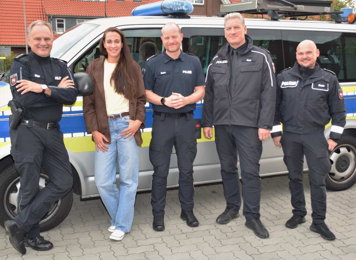 Fünf Personen vor Polizeifahrzeug.