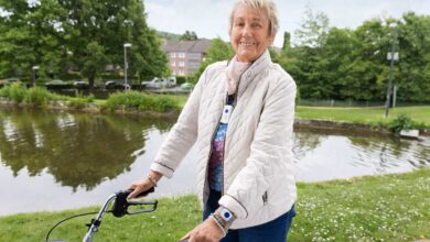 Frau mit Rollator am Wasser.