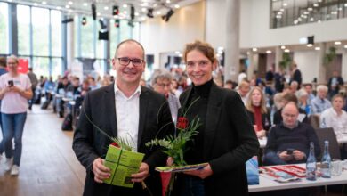 Zwei Personen mit Blumen und Unterlagen.