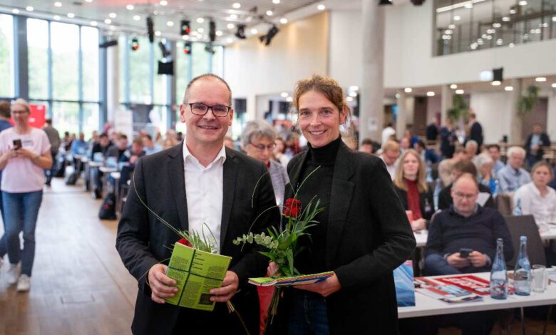 Zwei Personen mit Blumen und Unterlagen.