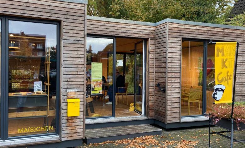Kaffeetafel und Klanggenuss: Pop-up-Box Maschen feiert Neustart am 25. Oktober 12 Holzgebäude mit Café und Pflanzen