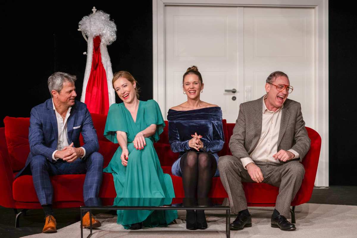 Vier Personen auf rotem Sofa.