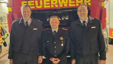 Drei Feuerwehrleute vor einem Fahrzeug