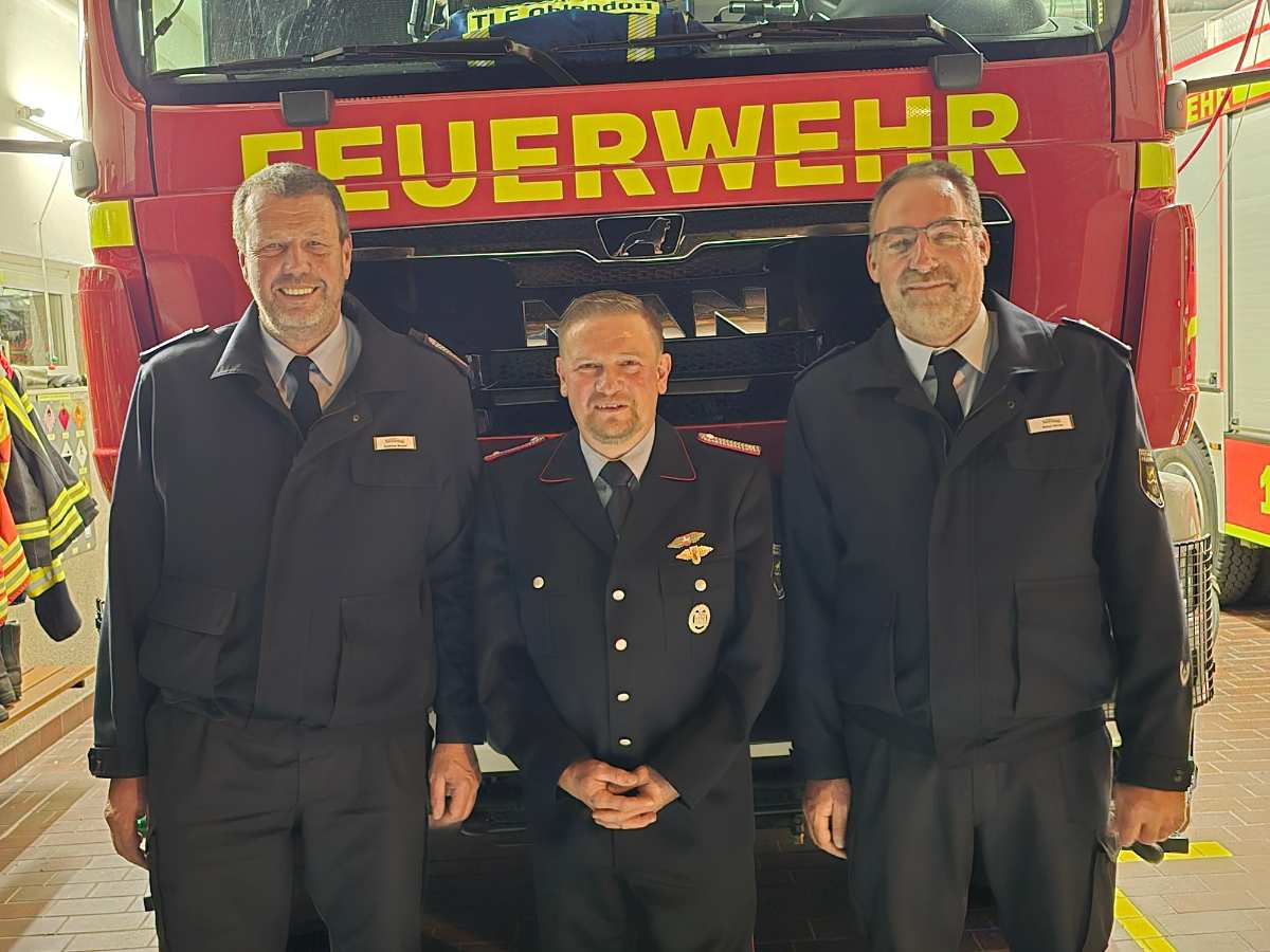 Drei Feuerwehrleute vor einem Fahrzeug
