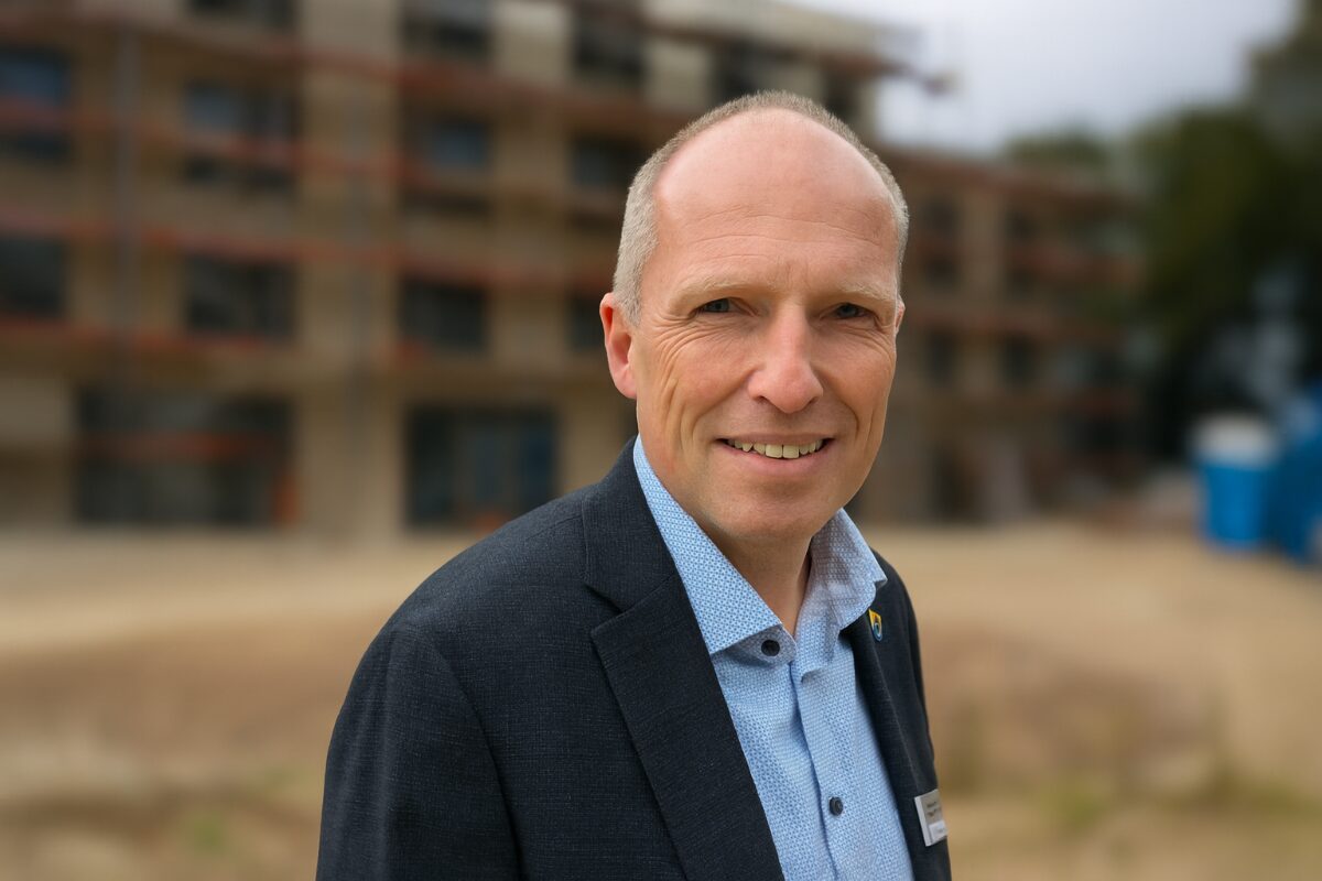 Mann vor Baustelle, seriös gekleidet.