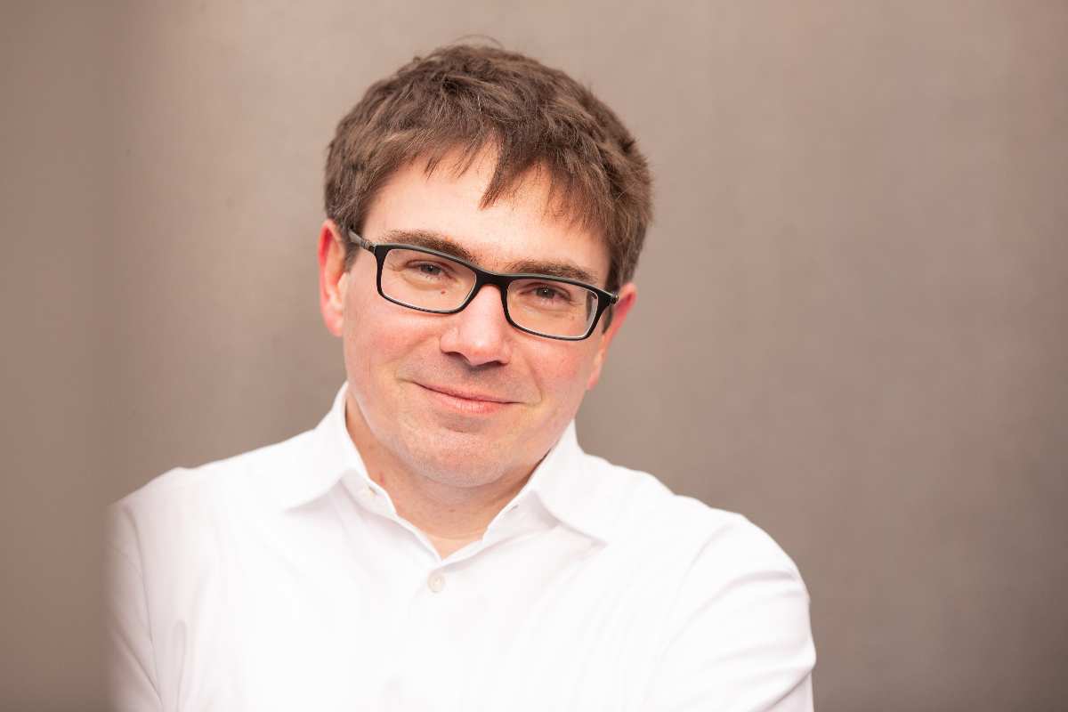 Mann mit weißem Hemd, neutraler Hintergrund.