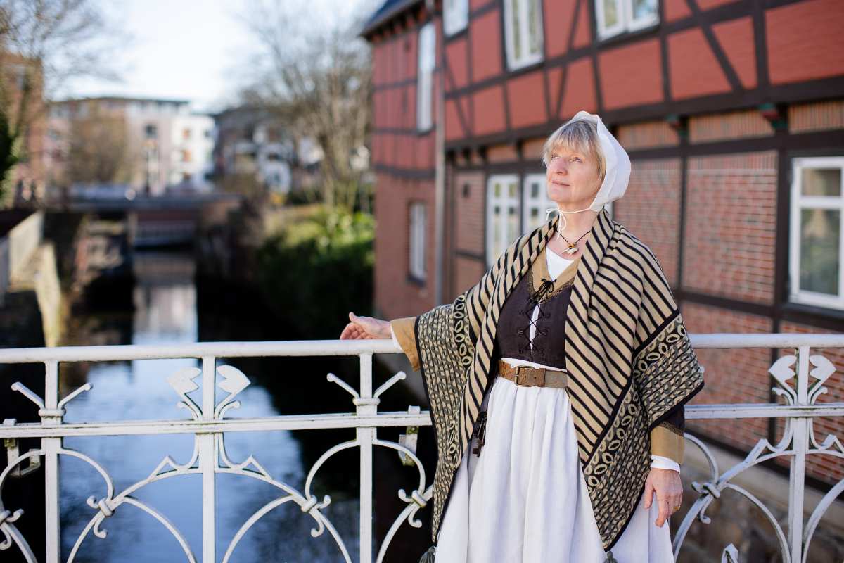 Frau in historischer Kleidung am Wasser.