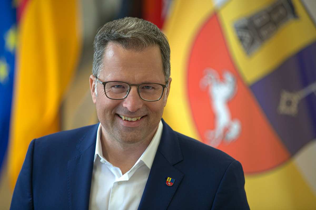 Mann in Anzug vor Flaggen