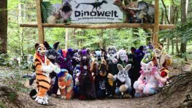 Furries posieren unter Dinosaurier-Schild.