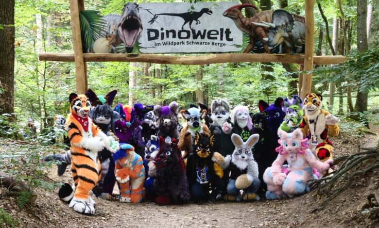 Rosengarten – Flauschige Fellwesen und Dino Lexi verzaubern Besucher im Wildpark Schwarze Berge 2 Furries posieren unter Dinosaurier-Schild.