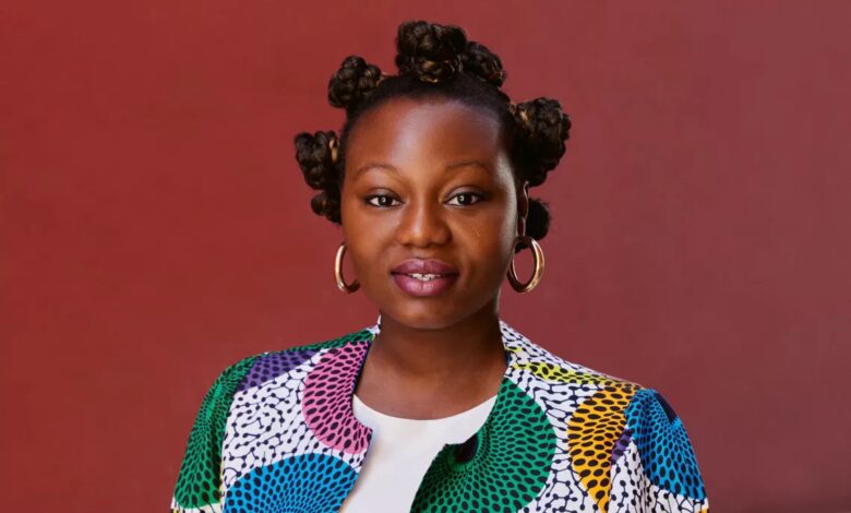 Mirrianne Mahn liest im Kulturhaus Süderelbe aus ihrem Debütroman „Issa“ 10 Farbige Kleidung vor rotem Hintergrund.