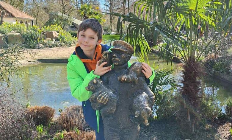 Junge mit Statue in der Natur.