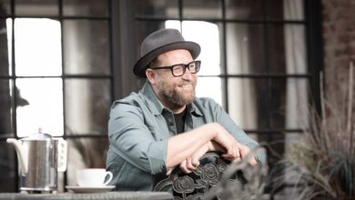 Mann mit Hut sitzt am Tisch.