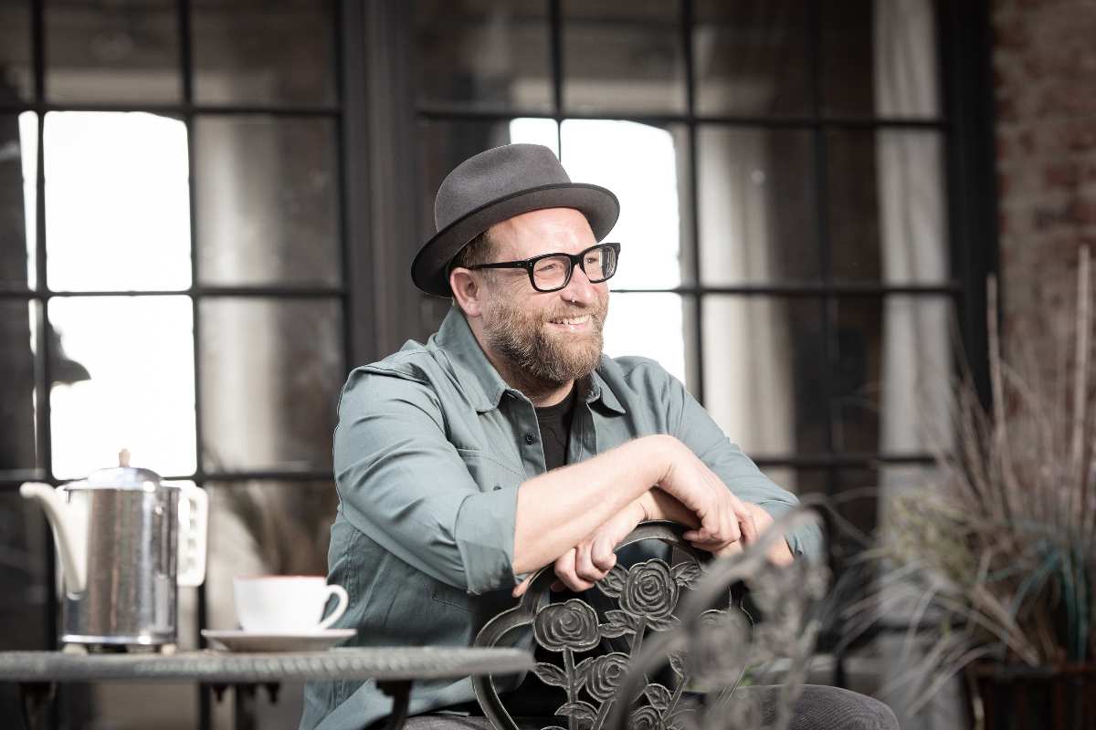 Mann mit Hut sitzt am Tisch.