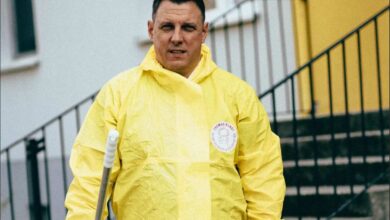 Mann in gelber Schutzkleidung mit Besen.