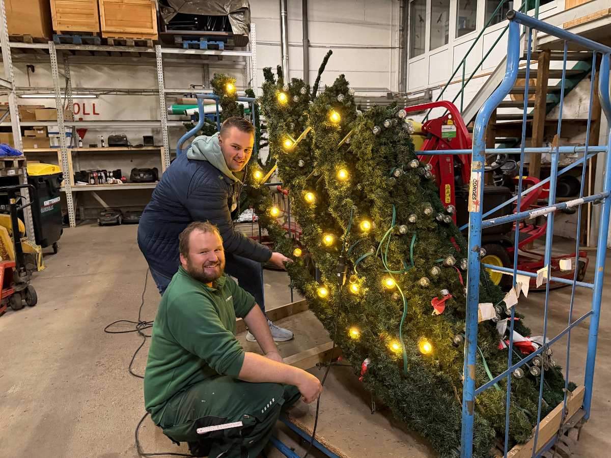 Zwei Personen dekorieren einen Weihnachtsbaum.