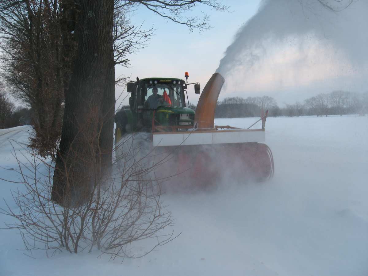 Schneepflug räumt verschneite Straße auf.