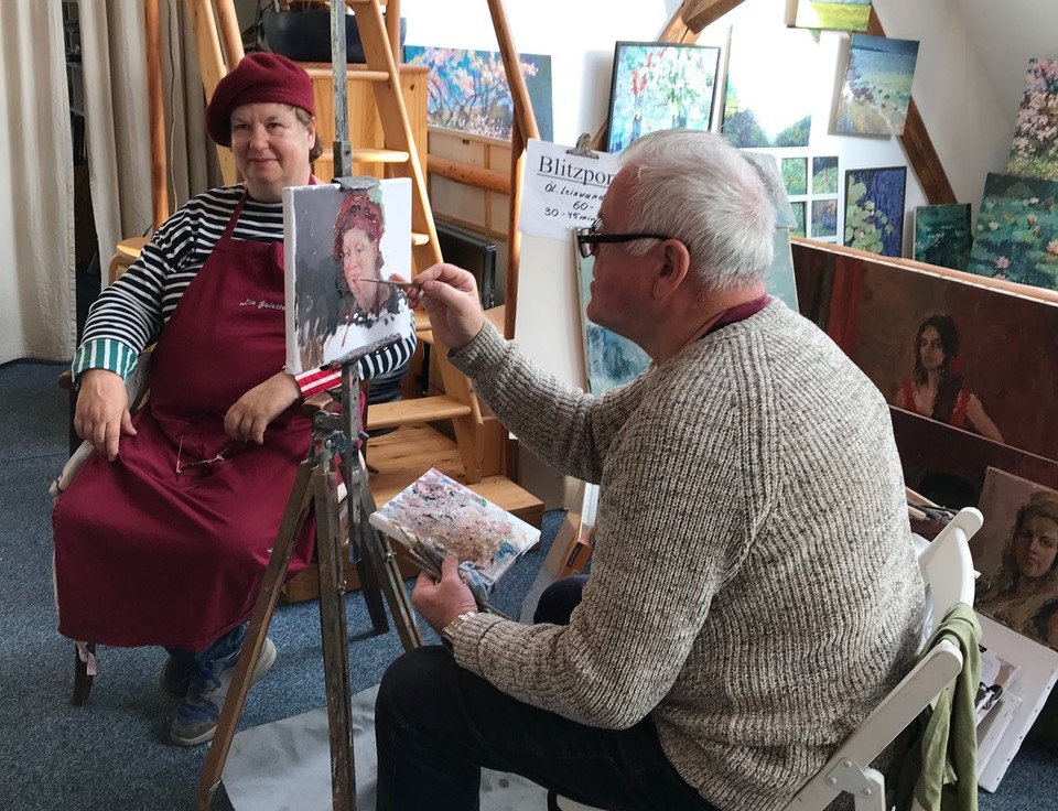 Mann malt Frau in Atelier.